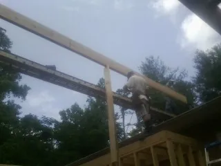 Carpenter setting a ridge beam over a new addition frame — Ice Dam Removal by Roofing Brothers in New Enterprise