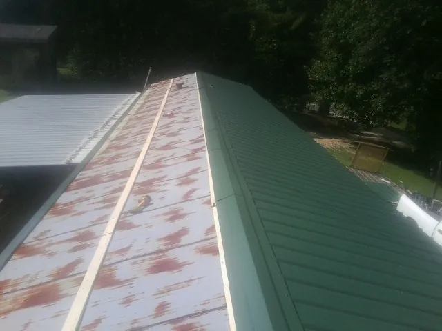 Old rusted panels beside newly installed green metal roofing — Wind Damage Roof Repair by Roofing Brothers in New Enterprise