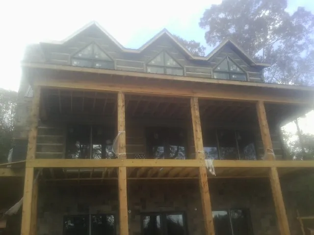 Dormers and porch framing on a large log home under construction — Roof Coating work by our crew in New Enterprise