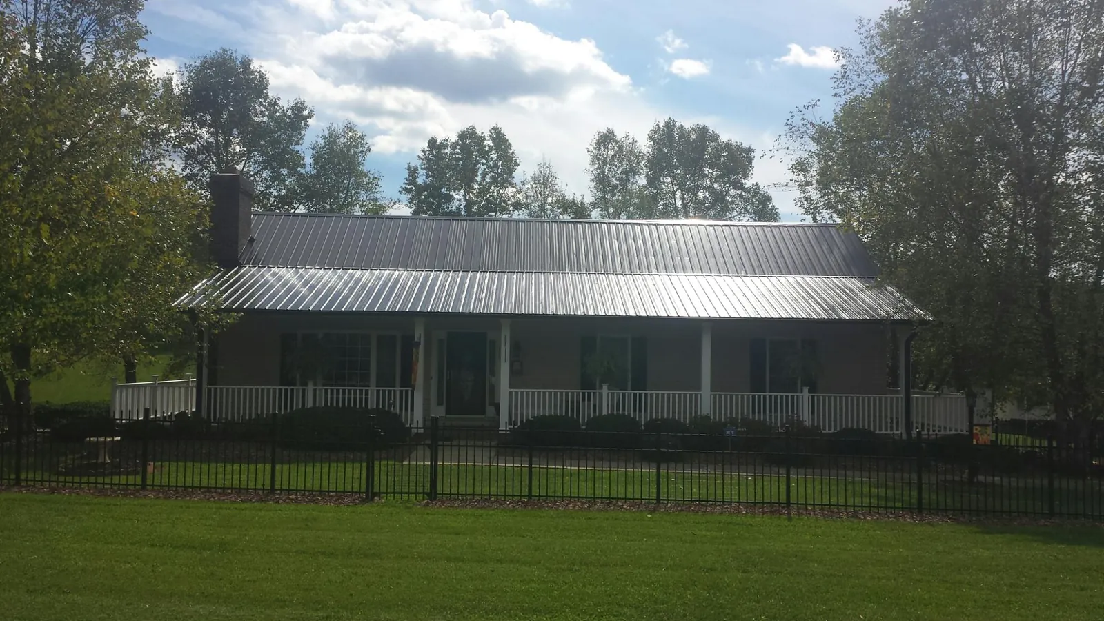 Gray metal roof on a brick ranch with a full width front porch — Gutter Guard Installation work by our crew in New Enterprise