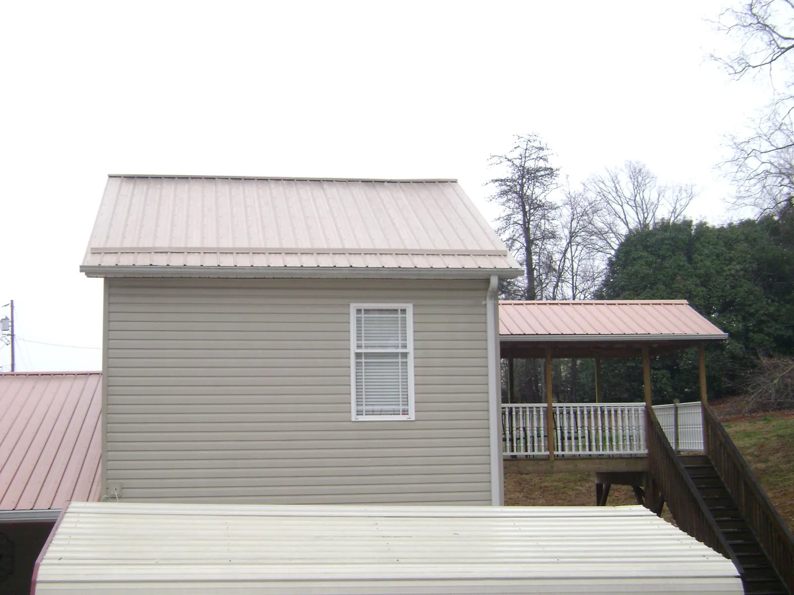 Tan metal roofs on a two story addition and attached porch, from a Roof Replacement job in New Enterprise
