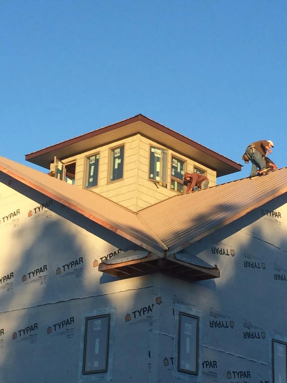 Roofers working around a rooftop cupola on a new metal roof at sunset — Roof Waterproofing in New Enterprise by Roofing Brothers